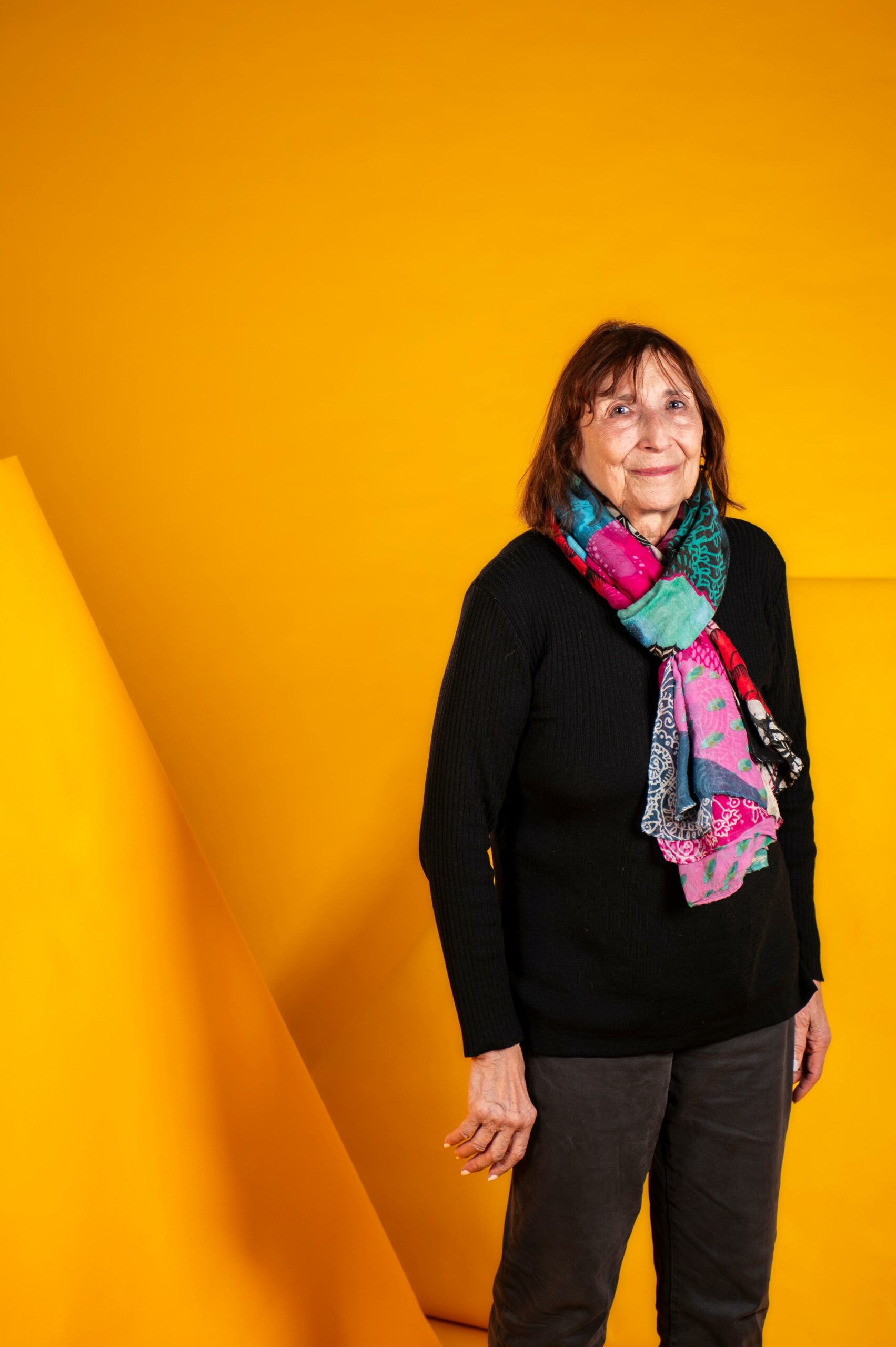 Portrait d’Elida Mannevy, fondatrice du Club Photo Malakoff, devant un fond jaune